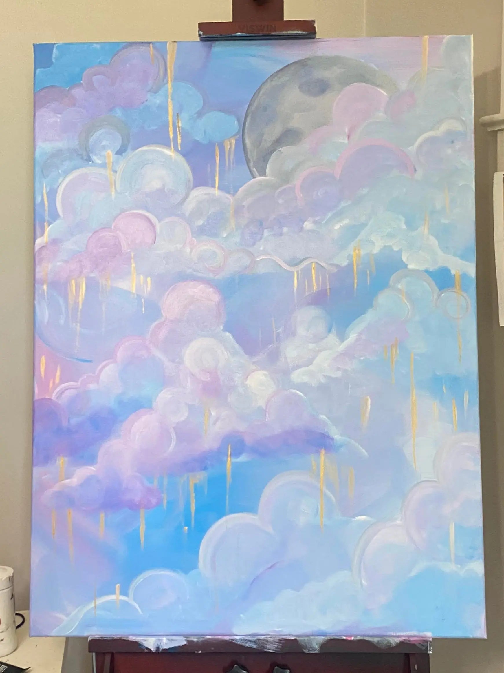 Soft clouds drift through a celestial dreamscape in Moonlit Reverie, where pastel pinks and lavenders mingle with serene blues under the watchful glow of a rising moon. Threads of gold cascade gently from the heavens, catching the light and adding a touch of the ethereal to the scene.